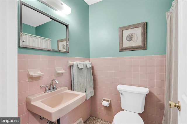 bathroom with sink, tile walls, and toilet