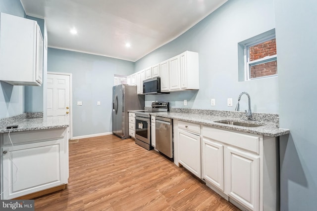 kitchen featuring sink, appliances with stainless steel finishes, white cabinetry, light stone countertops, and light wood-type flooring