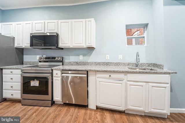 kitchen with sink, light stone counters, light wood-type flooring, appliances with stainless steel finishes, and white cabinets