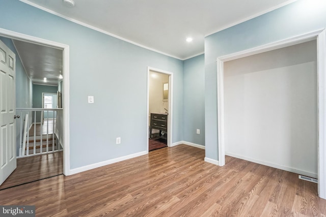 unfurnished bedroom featuring ornamental molding, connected bathroom, and light hardwood / wood-style floors