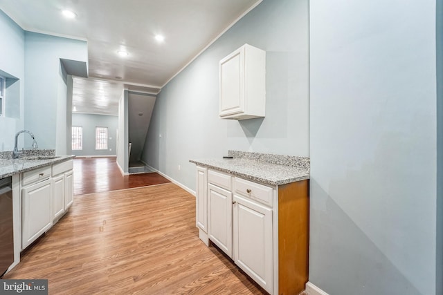 kitchen with light stone counters, sink, and white cabinets