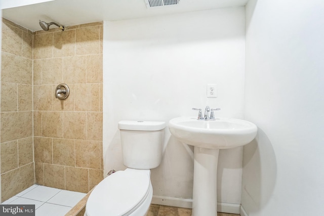 bathroom featuring a tile shower and toilet