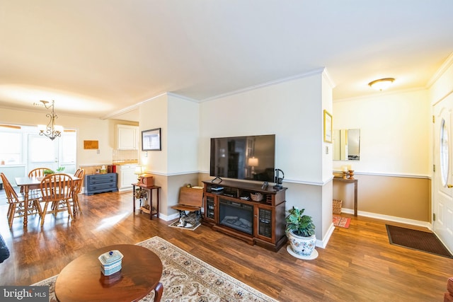 living room with wood-type flooring, ornamental molding, and a chandelier