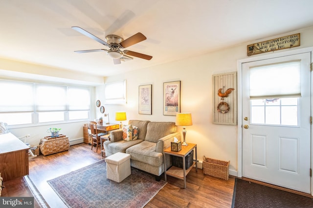 living room featuring ceiling fan, wood-type flooring, a baseboard radiator, and a healthy amount of sunlight