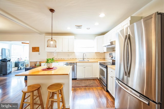 kitchen featuring butcher block countertops, sink, appliances with stainless steel finishes, white cabinets, and a kitchen island