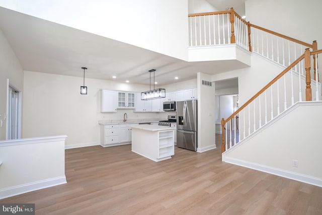 kitchen with white cabinetry, hanging light fixtures, stainless steel appliances, and a kitchen island