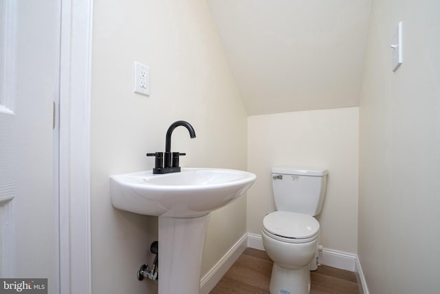 bathroom with hardwood / wood-style flooring, lofted ceiling, and toilet