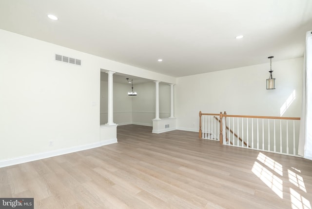 unfurnished room with light hardwood / wood-style flooring and ornate columns