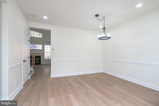 unfurnished dining area featuring an inviting chandelier and light wood-type flooring