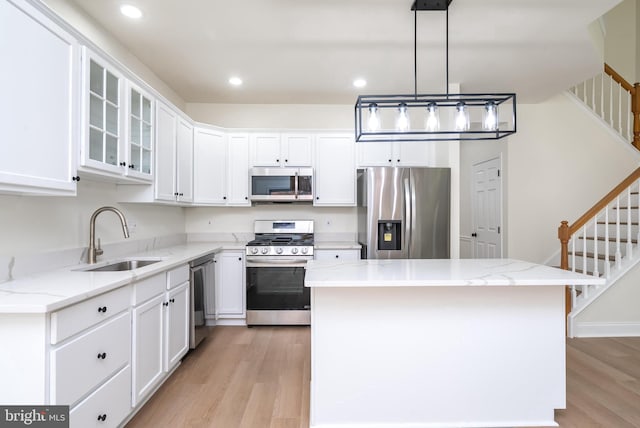 kitchen featuring pendant lighting, sink, appliances with stainless steel finishes, a center island, and white cabinets