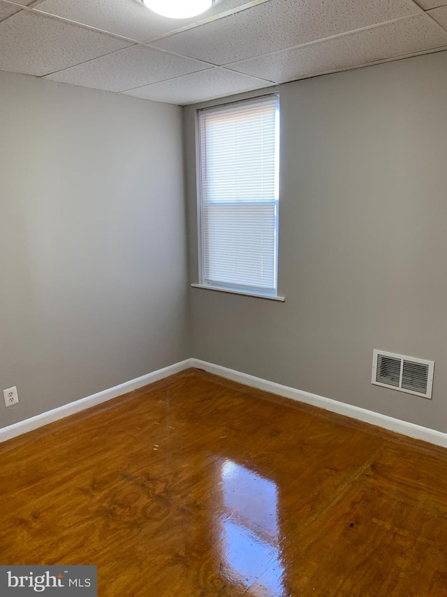 empty room featuring hardwood / wood-style flooring and a drop ceiling