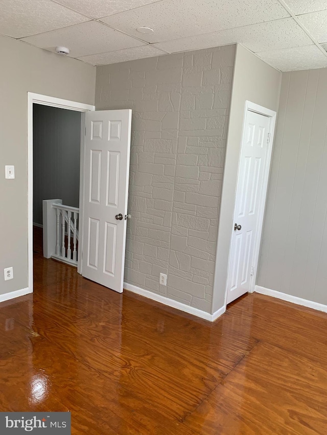 empty room featuring wood-type flooring and a paneled ceiling