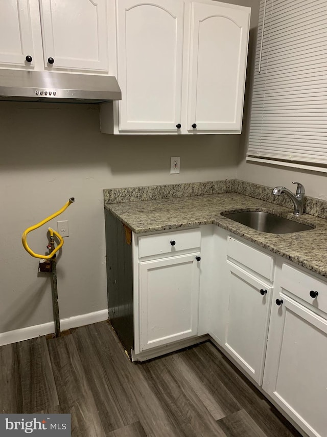 kitchen with light stone counters, dark hardwood / wood-style floors, sink, and white cabinets