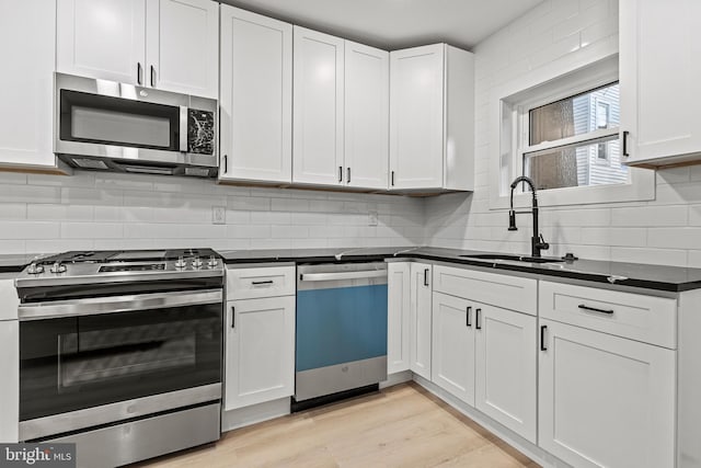 kitchen with white cabinetry, appliances with stainless steel finishes, sink, and light wood-type flooring