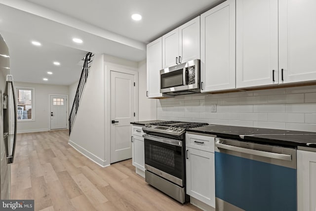 kitchen featuring tasteful backsplash, light wood-type flooring, white cabinets, and appliances with stainless steel finishes