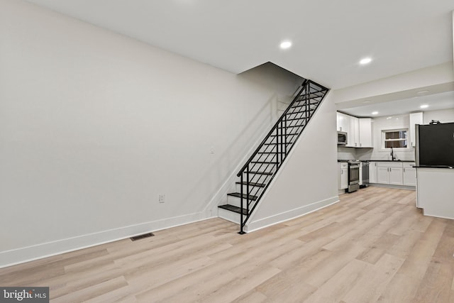 unfurnished living room featuring sink and light wood-type flooring