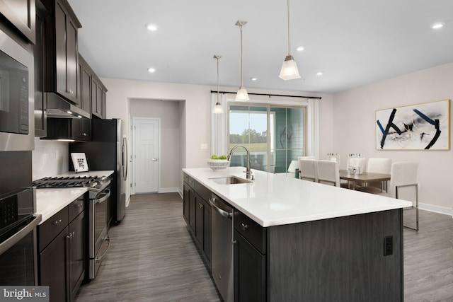 kitchen featuring a sink, appliances with stainless steel finishes, an island with sink, and light countertops