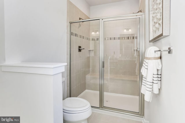 bathroom with tile patterned flooring, a shower stall, and toilet