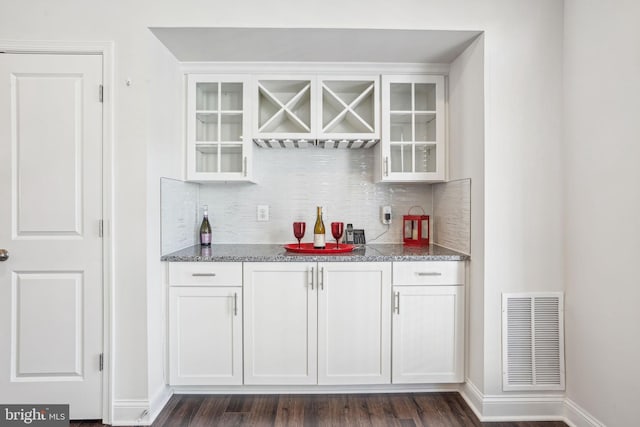 bar with decorative backsplash, dark wood-style floors, visible vents, and baseboards