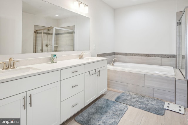 bathroom featuring a sink, a garden tub, a stall shower, and double vanity