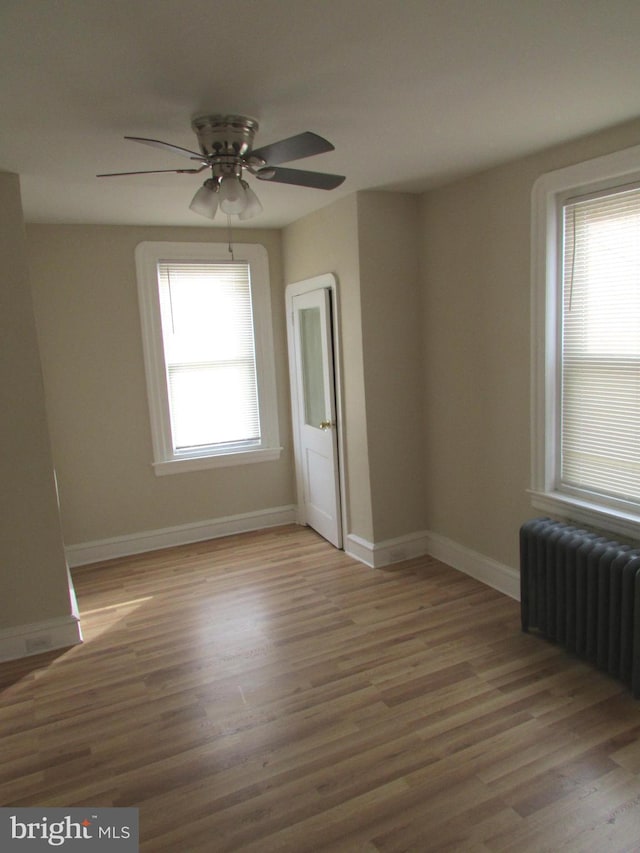 empty room featuring light hardwood / wood-style flooring, radiator heating unit, and a healthy amount of sunlight