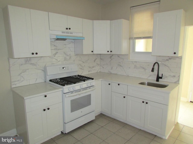 kitchen featuring white range with gas cooktop, sink, white cabinets, and decorative backsplash