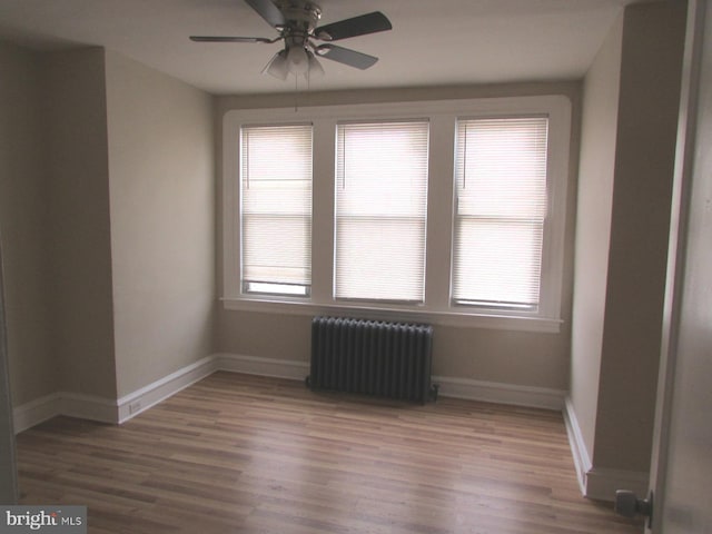 spare room with ceiling fan, plenty of natural light, radiator, and hardwood / wood-style floors