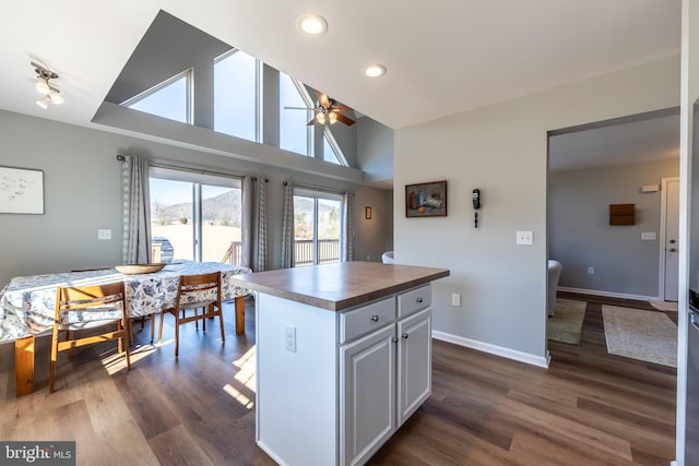 kitchen with ceiling fan, dark hardwood / wood-style floors, a center island, and white cabinets