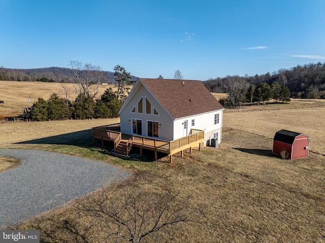 exterior space with a wooden deck, a yard, a rural view, and a storage unit