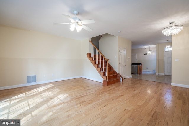 spare room featuring ceiling fan with notable chandelier and light hardwood / wood-style floors