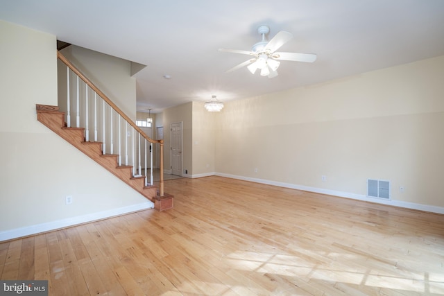 unfurnished living room featuring ceiling fan with notable chandelier and light hardwood / wood-style floors