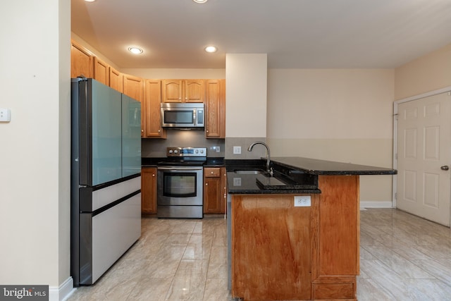 kitchen with appliances with stainless steel finishes, sink, a breakfast bar area, and dark stone counters