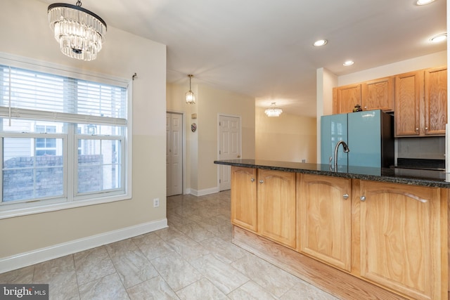 kitchen featuring fridge, pendant lighting, a notable chandelier, and dark stone counters