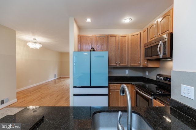 kitchen featuring dark stone countertops, sink, light hardwood / wood-style flooring, and appliances with stainless steel finishes