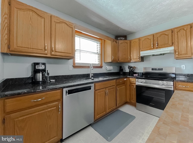 kitchen with stainless steel appliances, butcher block counters, a sink, a textured ceiling, and under cabinet range hood