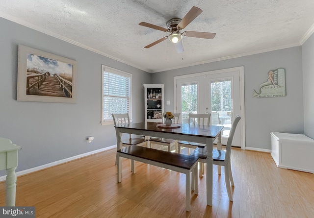 dining area featuring crown molding, french doors, plenty of natural light, and light wood-style flooring