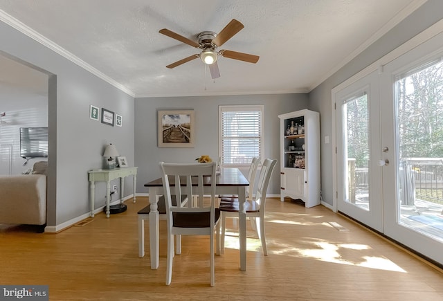 dining room featuring french doors, crown molding, light wood finished floors, a textured ceiling, and baseboards