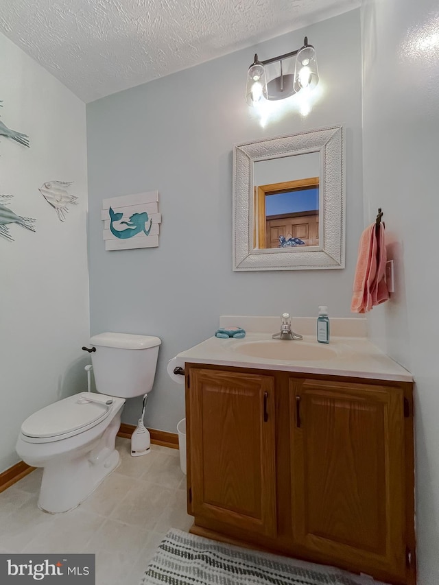 half bathroom featuring toilet, a textured ceiling, vanity, and baseboards