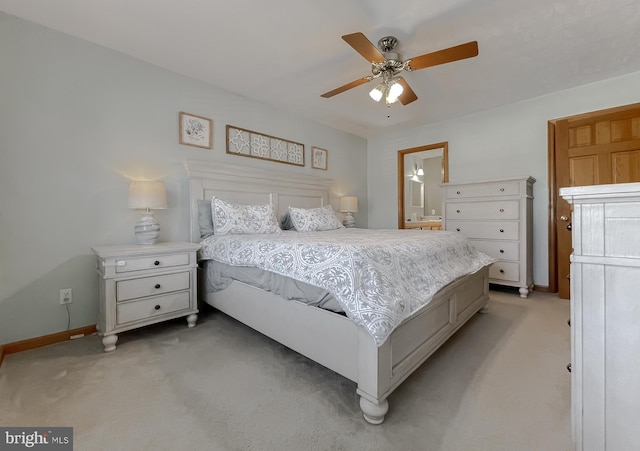 bedroom with light carpet, ensuite bath, baseboards, and a ceiling fan