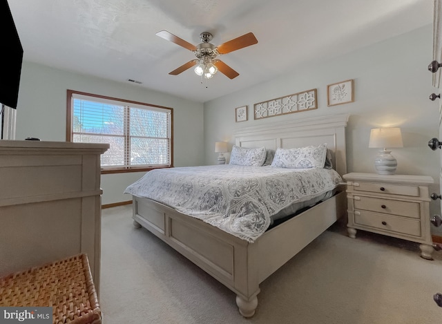 bedroom with ceiling fan, visible vents, baseboards, and light colored carpet