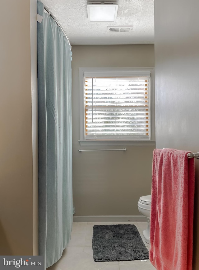 full bathroom with baseboards, visible vents, toilet, tile patterned flooring, and a textured ceiling