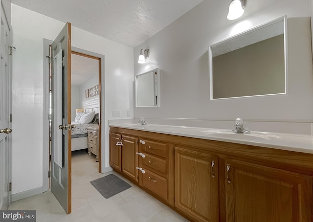 full bath with a sink, double vanity, a textured ceiling, and ensuite bath