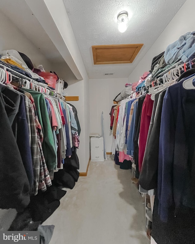 spacious closet with attic access and light colored carpet