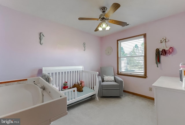 bedroom with light carpet, ceiling fan, a nursery area, and baseboards