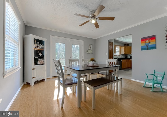 dining space featuring a textured ceiling, french doors, light wood finished floors, and a healthy amount of sunlight