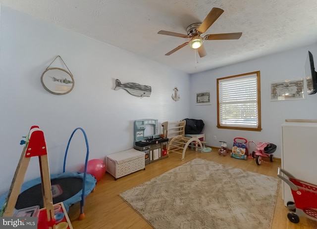 rec room featuring a textured ceiling, wood finished floors, and a ceiling fan