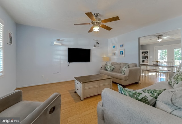 living room with ceiling fan, baseboards, and light wood-style floors