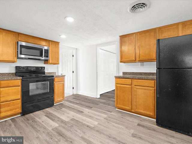 kitchen with a textured ceiling, light wood-type flooring, and black appliances
