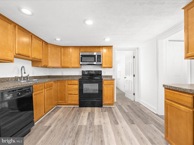 kitchen with sink, black appliances, light hardwood / wood-style floors, and a textured ceiling
