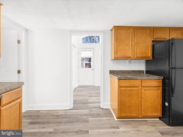 kitchen featuring black fridge, light hardwood / wood-style floors, and a textured ceiling